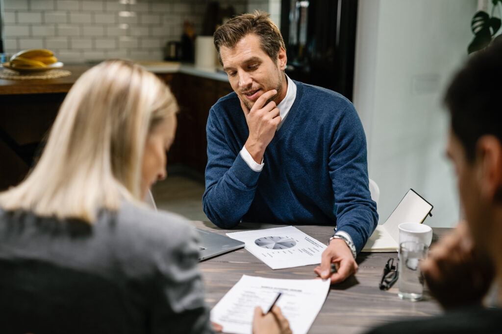 A lender and a couple signing a loan agreement after a consultation