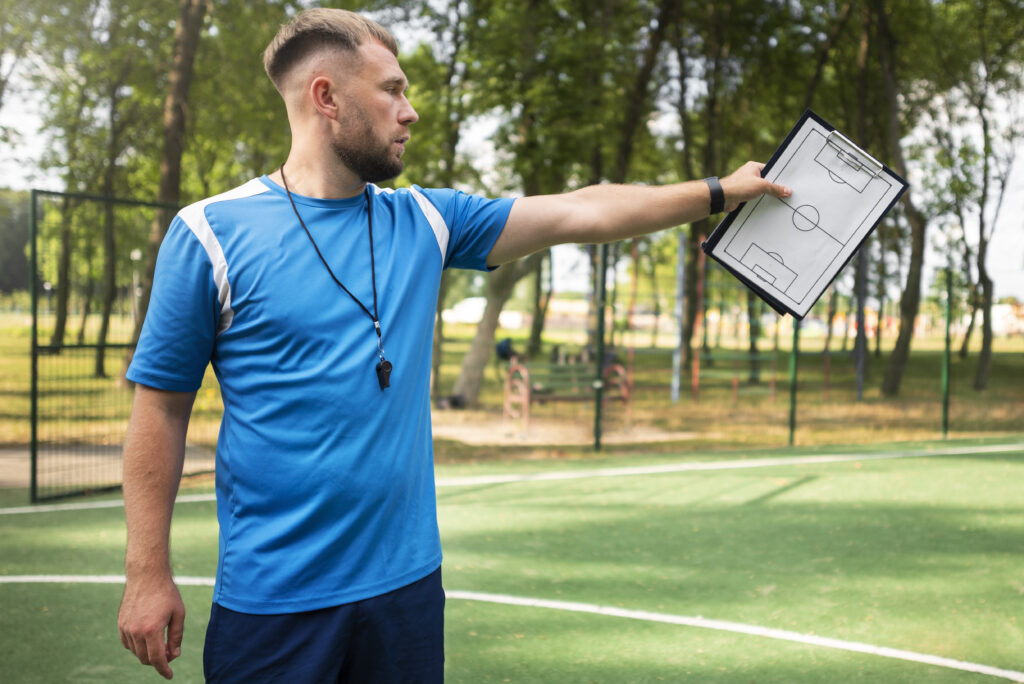 A football coach teaching young players at a club session