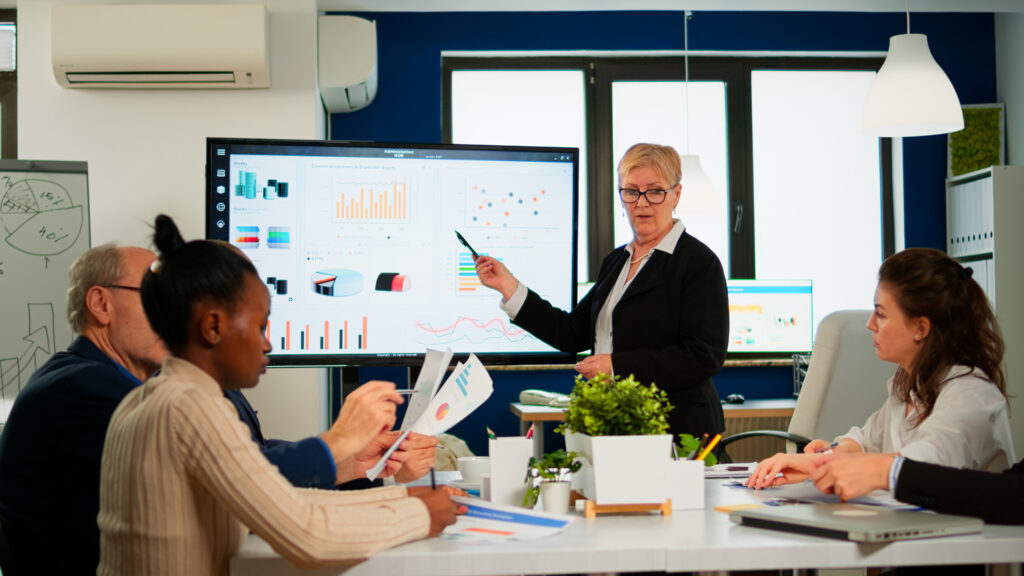 A presenter walking a team through growth charts on a digital whiteboard