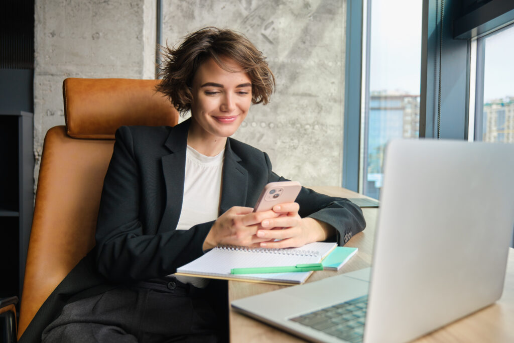 A sales professional running outreach on her laptop and phone